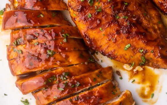 close up of a sliced chicken breast on a white plate.