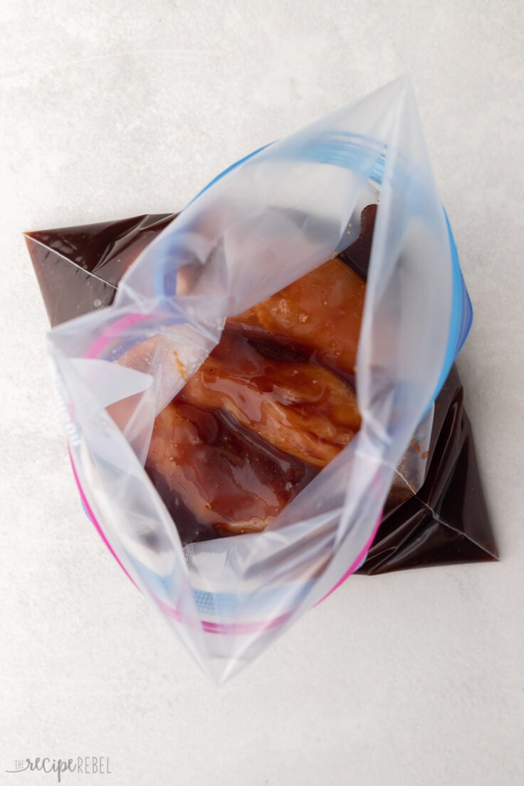 open plastic bag filled with chicken and marinade.