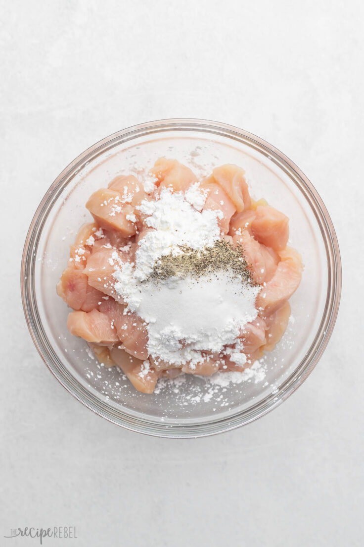 glass mixing bowl with cubed chicken and dry ingredients added.