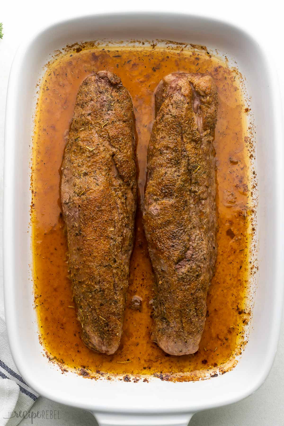 white baking dish with two baked tenderloins in.