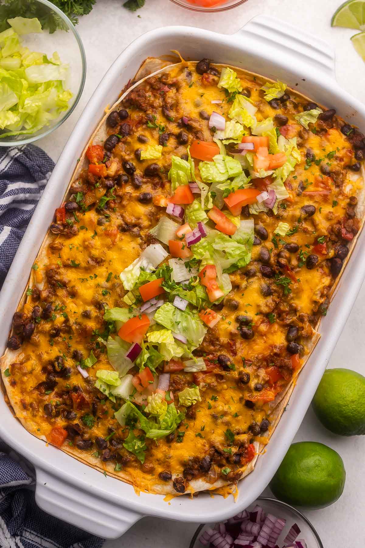 a full baking dish of taco casserole topped with chopped tomatoes and lettuce.