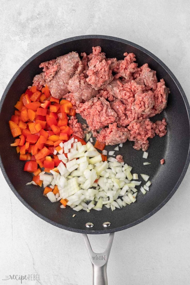 black frying pan with onions, peppers and ground beef.