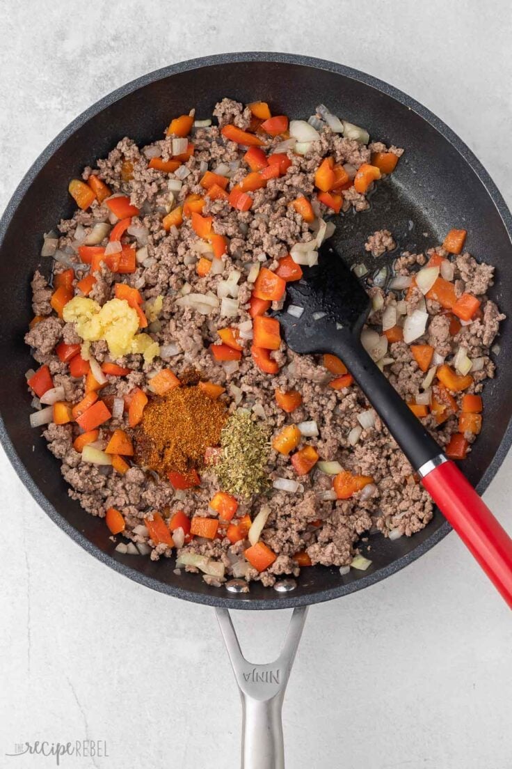 cooked ground beef in frying pan with seasonings added.