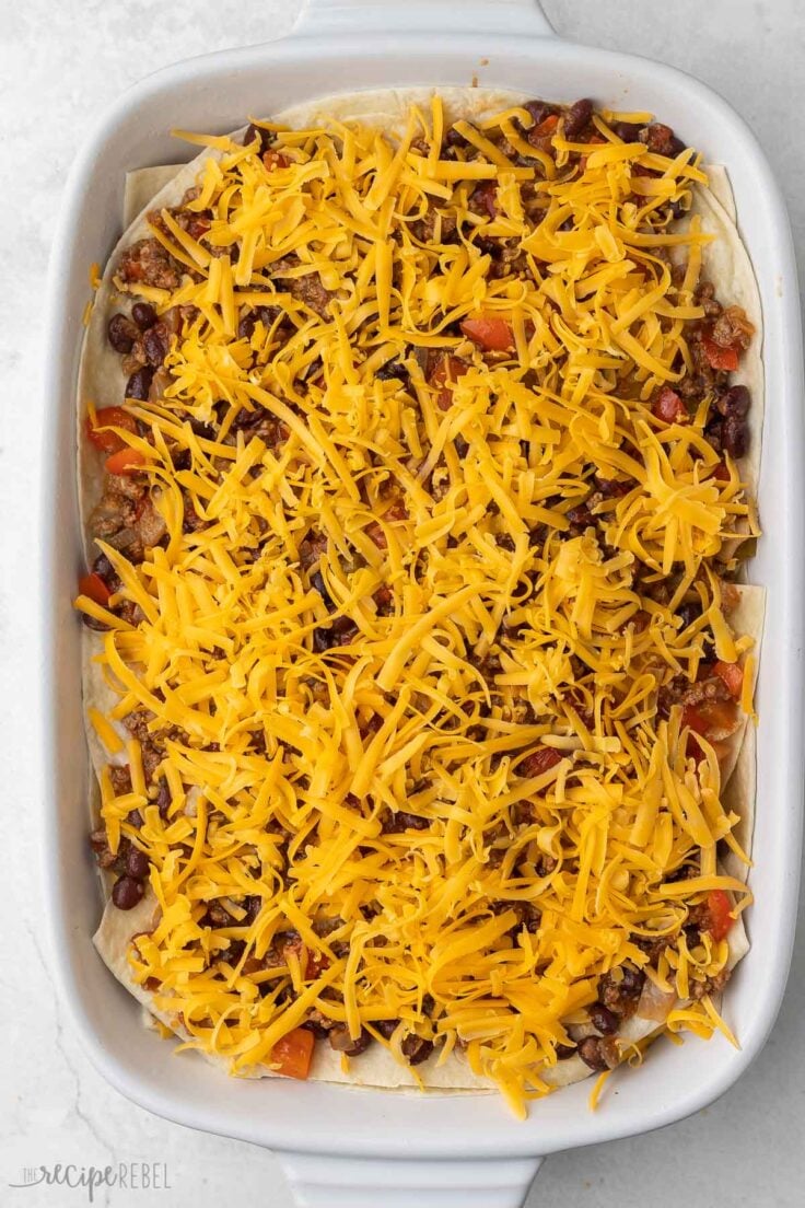 taco casserole in baking dish with shredded cheese on top.