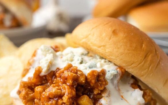 Buffalo chicken sloppy joes are placed on white plates.