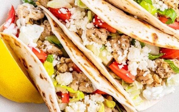 Greek chicken tacos are on a white plate.