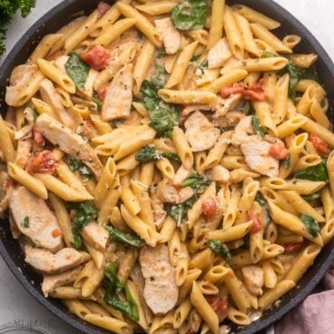 close up of a pan of chicken penne pasta topped with parmesan.