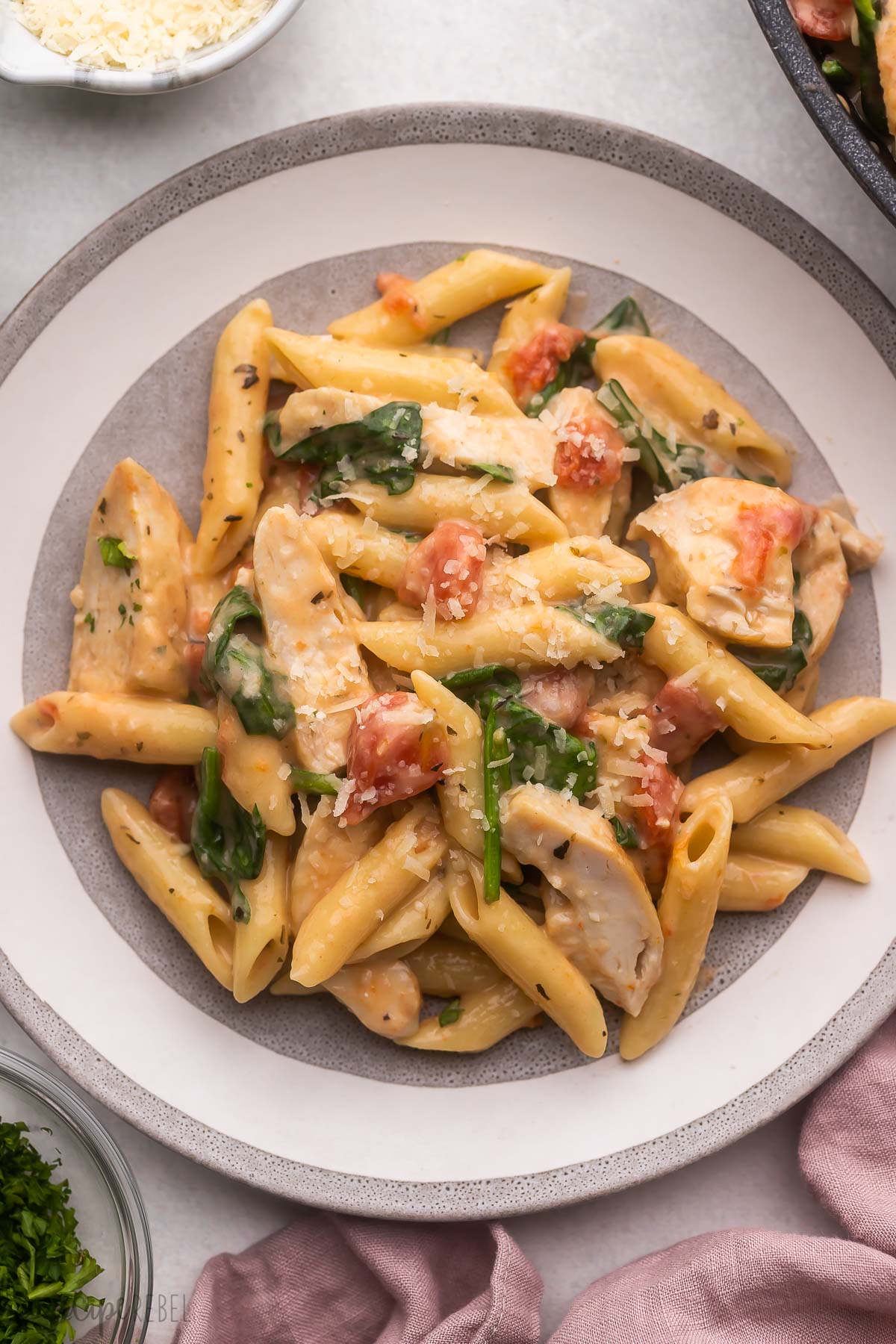 a plate filled with chicken penne pasta and topped with parmesan.