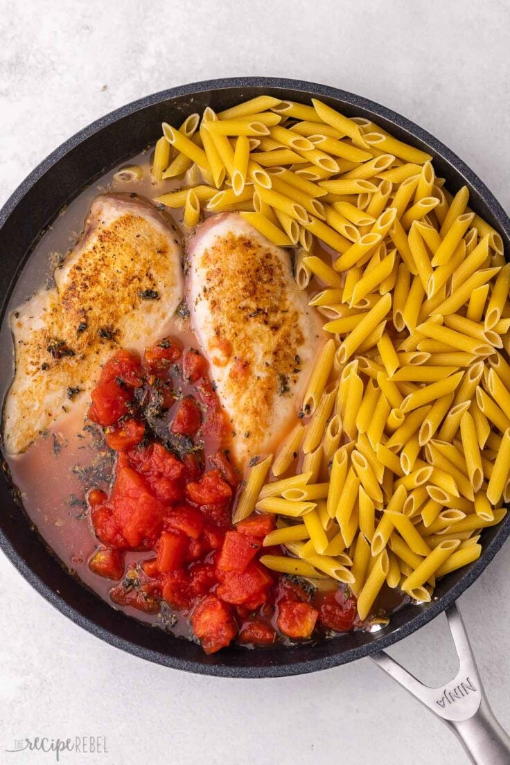 penne added to other ingredients in black frying pan.