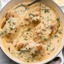 large white pan full of creamy tuscan chicken and a spoon.