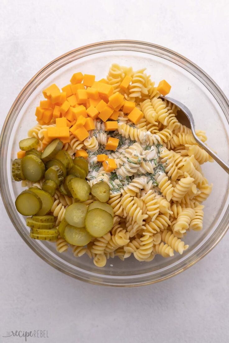glasss bowl with pasta and other ingredients added to top.
