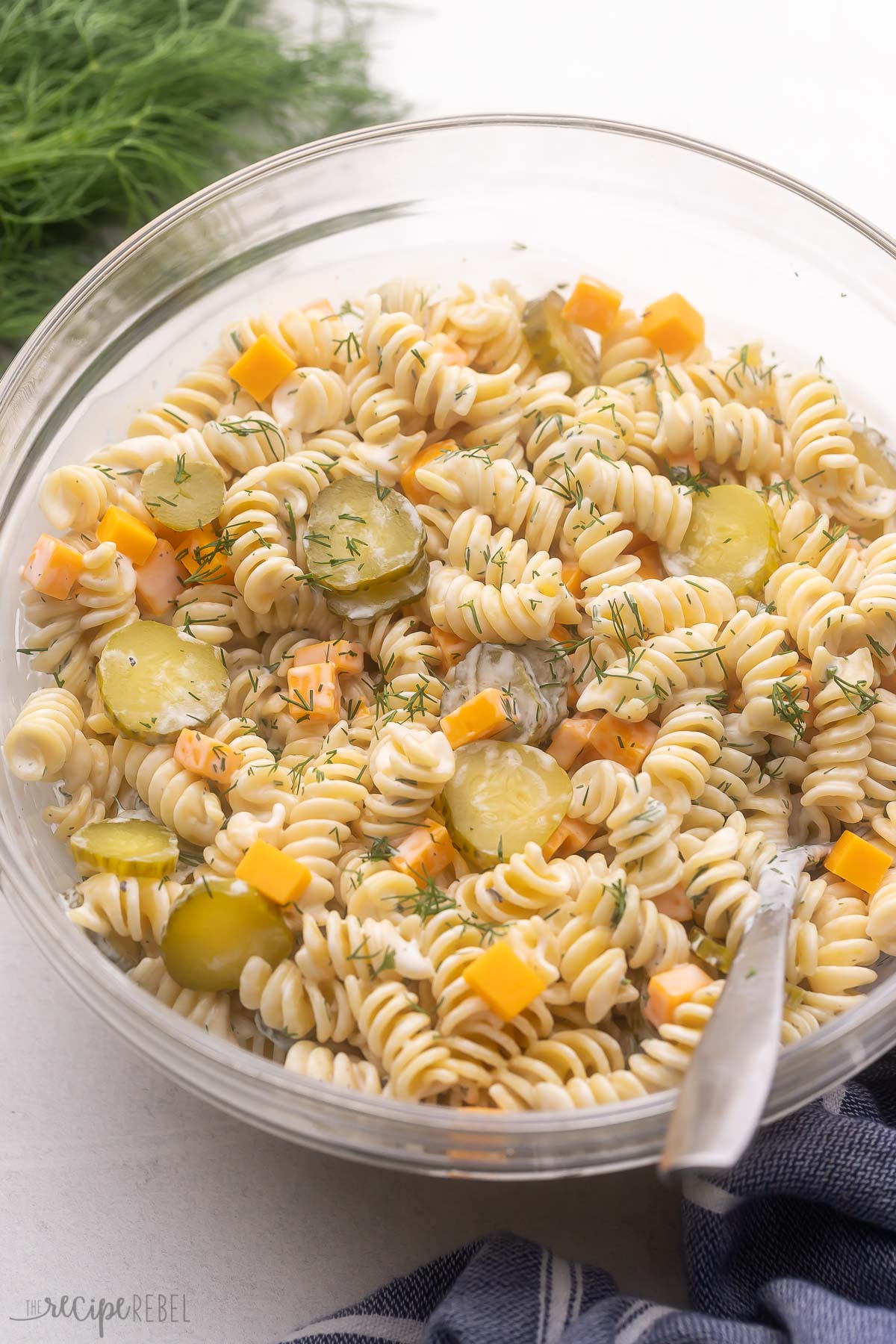 bowl of dill pickle pasta salad with fresh dill behind it.