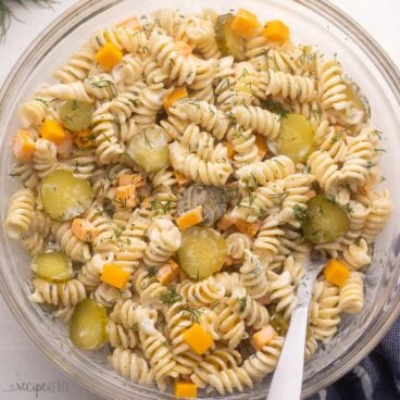 glass bowl filled with dill pickle pasta salad and spoon.