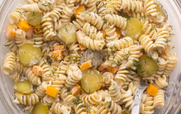 glass bowl filled with dill pickle pasta salad and spoon.