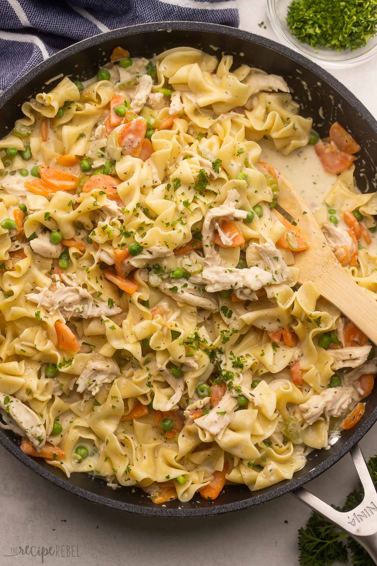 large pan with wooden ladle and chicken and noodles.