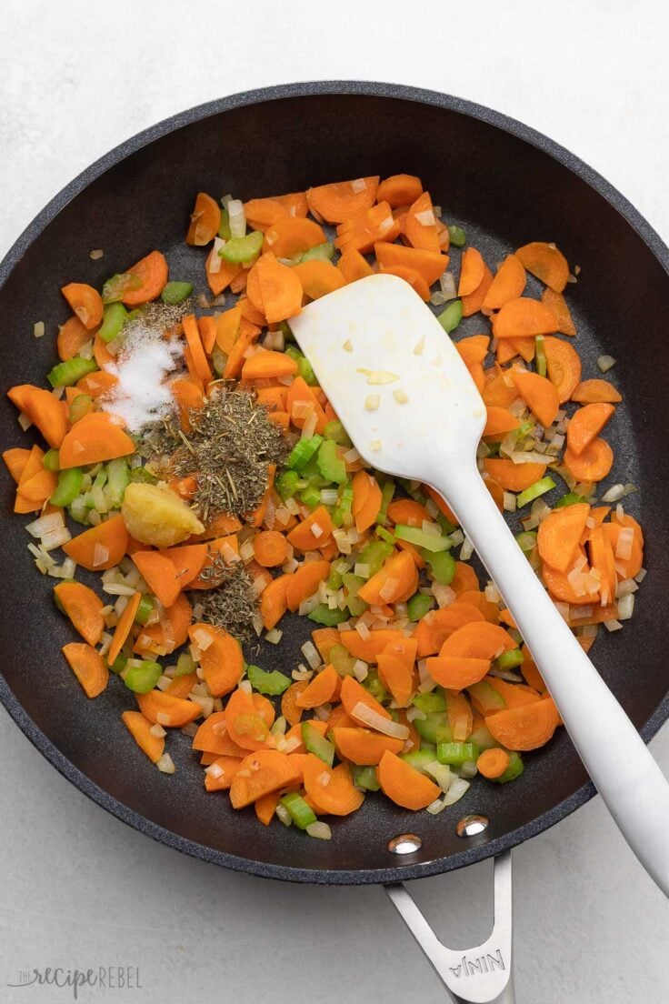 spices added on top of sauteed vegetables in frying pan.