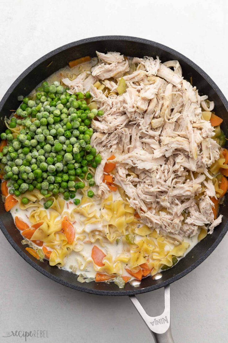 large pan with shredded chicken added on top of other ingredients.