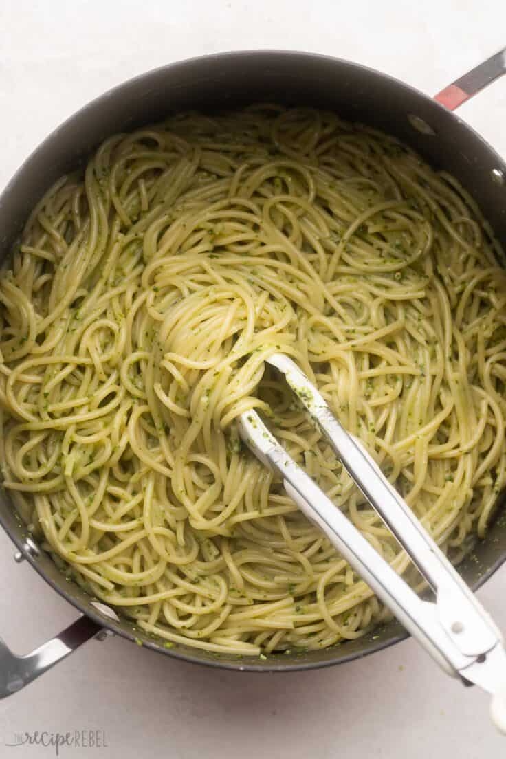 mixed pot of pasta with pesto sauce on grey surface.