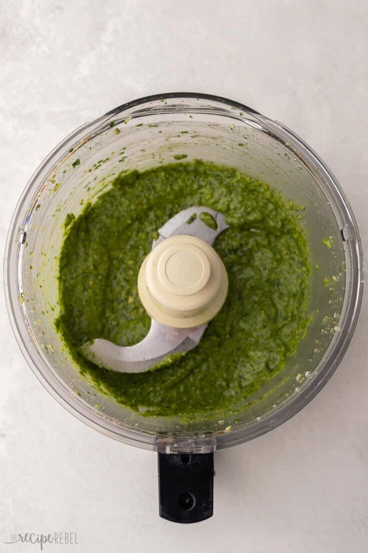 food processor filled processed pesto ingredients.