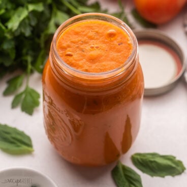 glass jar filled with roasted tomato sauce and basil beside.