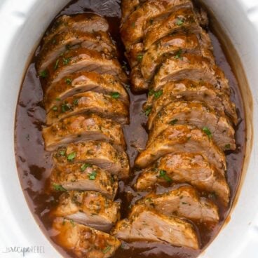 pork tenderloin sliced and covered in glaze in a white slow cooker.