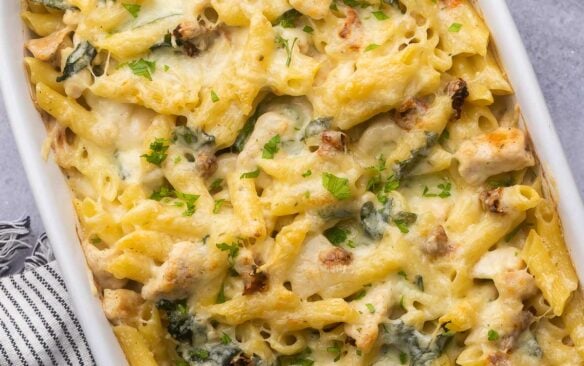 square image for tuscan chicken pasta bake in white baking dish.