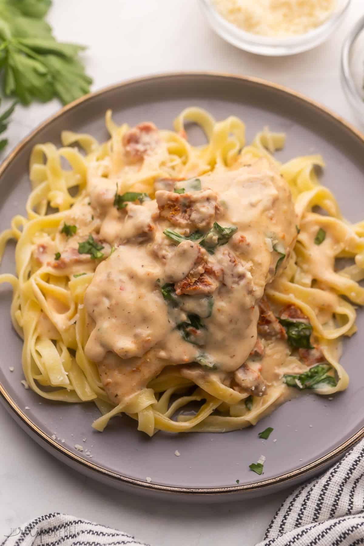 grey plate with pasta topped with tuscan chicken.