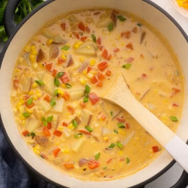 close shot of a large pot of southwest corn chowder in black pot with wooden ladle.