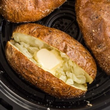 square image of air fryer baked potato in air fryer basket.