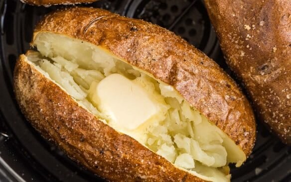 square image of air fryer baked potato in air fryer basket.