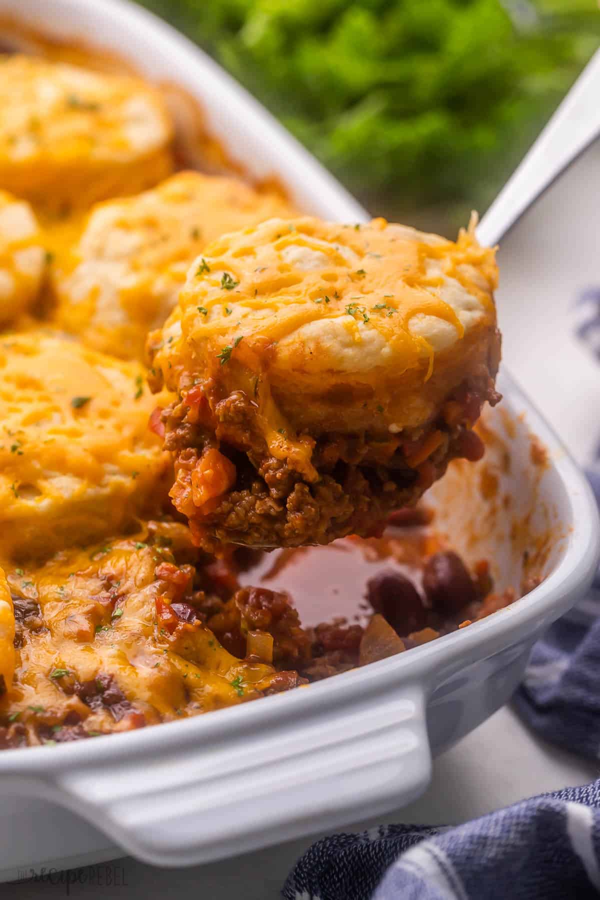 large white pan of bbq chili cheese casserole with a biscuit being scooped out.