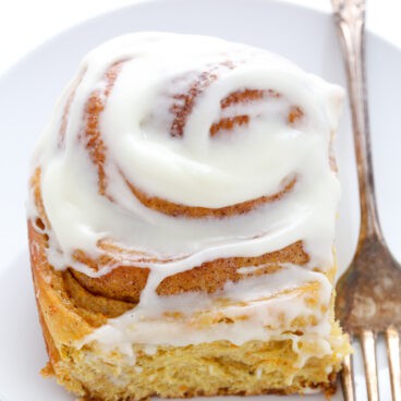 carrot cake cinnamon roll on white plate.