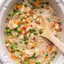 a wooden ladle inside a slow cooker filled with chicken and rice.