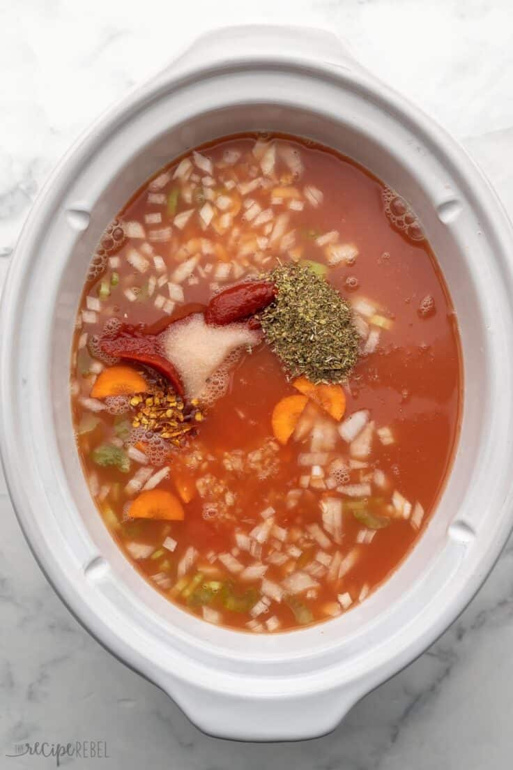 unstirred ingredients for creamy tomato soup in white slow cooker.
