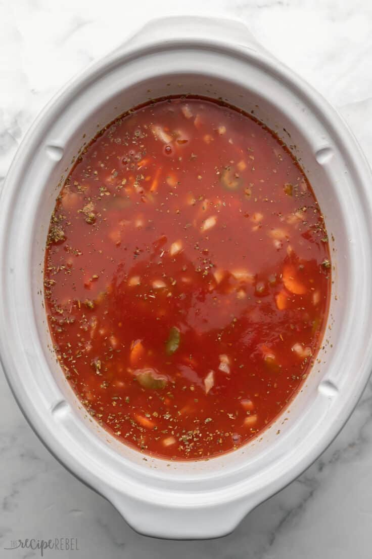 white slow cooker filled with ingredients for creamy tomato soup.