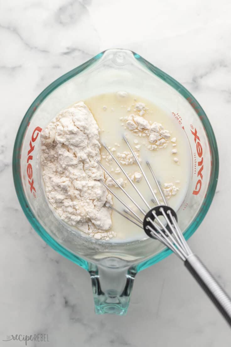 glass measuring cup with steel whisk and ingredients.