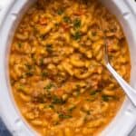 close up of slow cooker hamburger helper with a large spoon in it.