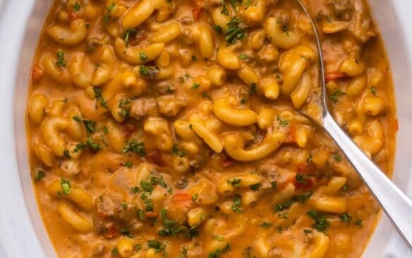 close up of slow cooker hamburger helper with a large spoon in it.