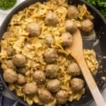 close up of swedish meatballs and noodles in a black pan.