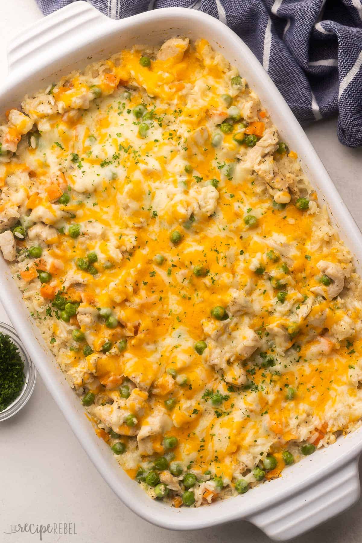 Cheesy Chicken and Rice Casserole is the definition of comfort food! White rice and chicken breasts are baked in a casserole dish to creamy and cheesy perfection. There's also a good amount of veggies in there for those picky eaters at your table! #chicken #dinner #recipe | chicken recipe | chicken breast recipe | dinner ideas | easy dinner recipes | casserole recipes | healthy dinner | family dinner overhead view of chicken and rice casserole in a white dish.