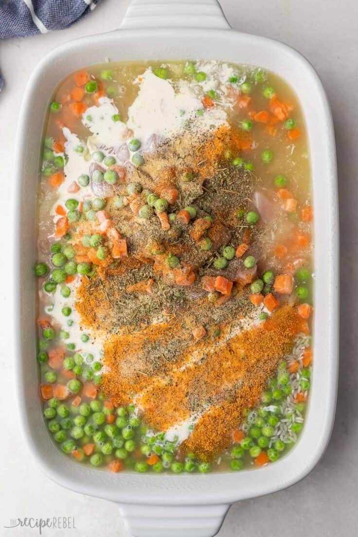 white baking dish filled with broth, frozen vegetables and other ingredients.