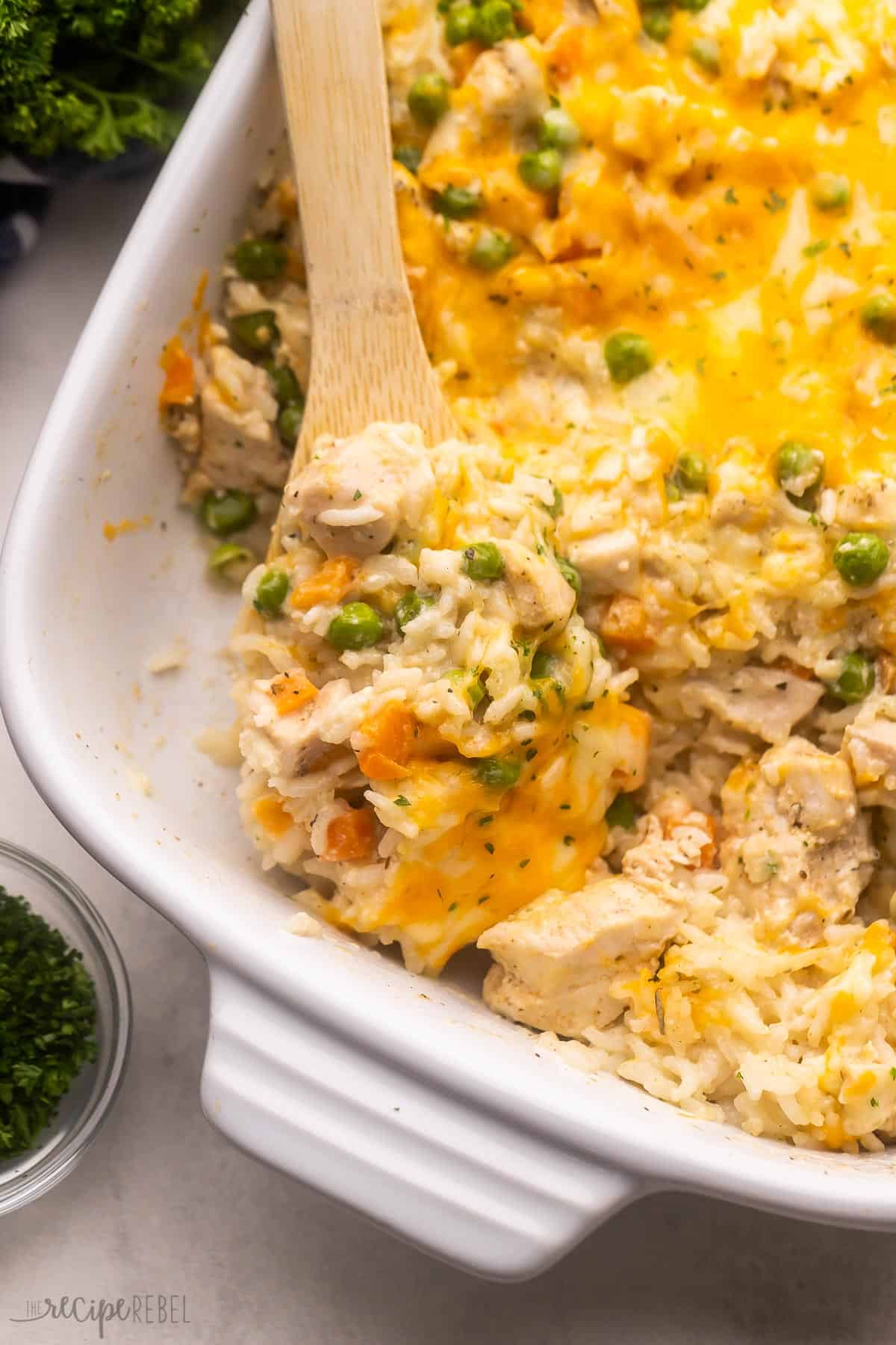 wooden ladle scooping chicken and rice casserole out of casserole dish.