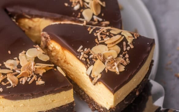 close up of a piece of no bake nanaimo bar cheesecake being lifted off plate.