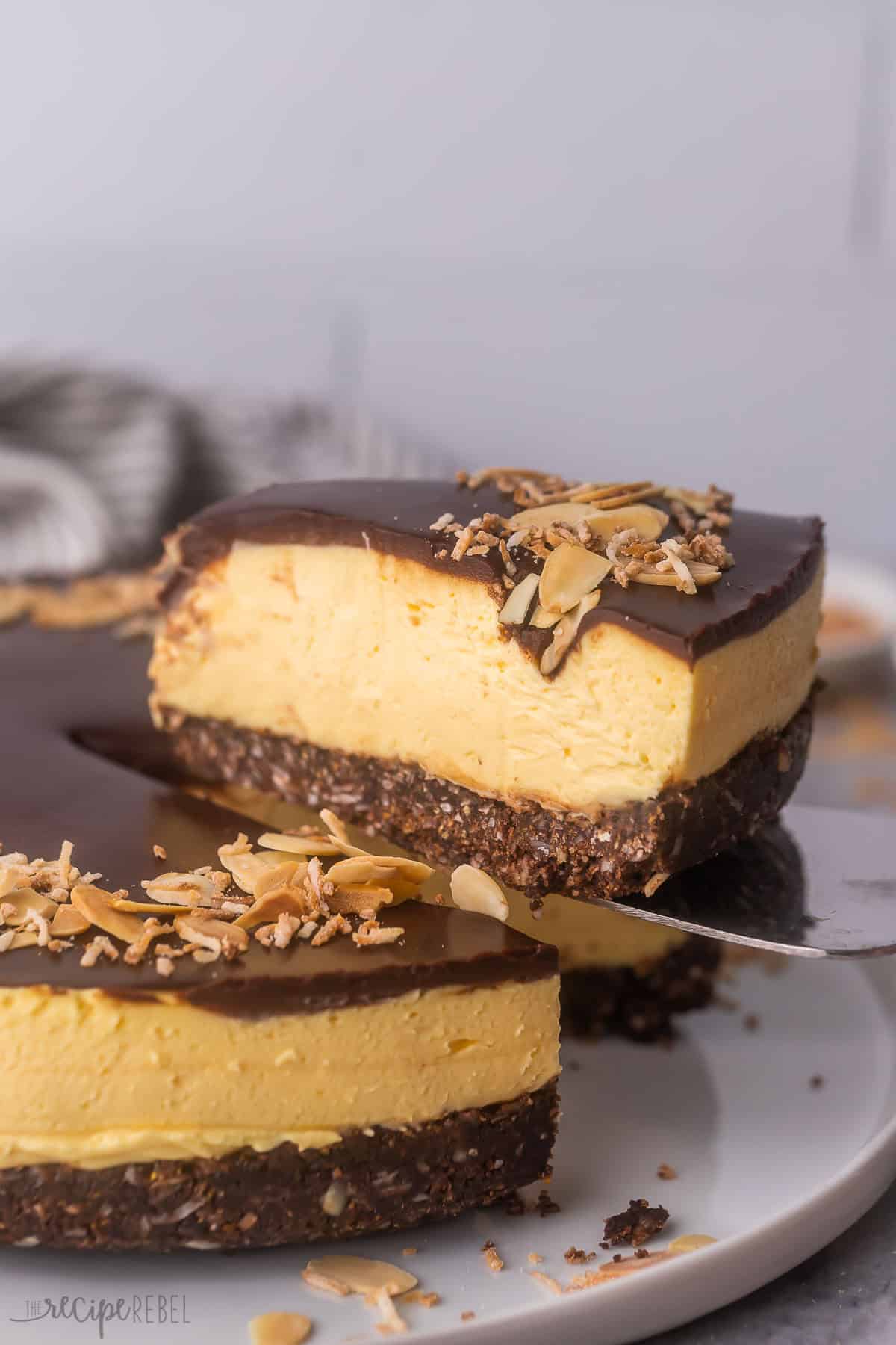 side shot of a piece of nanaimo bar cheesecake being lifted out of cake.