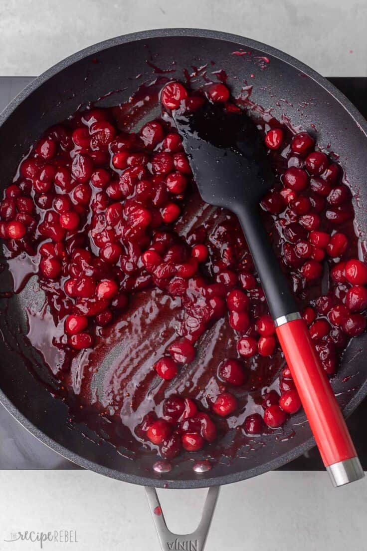 black pan filled with cranberries and spatula.