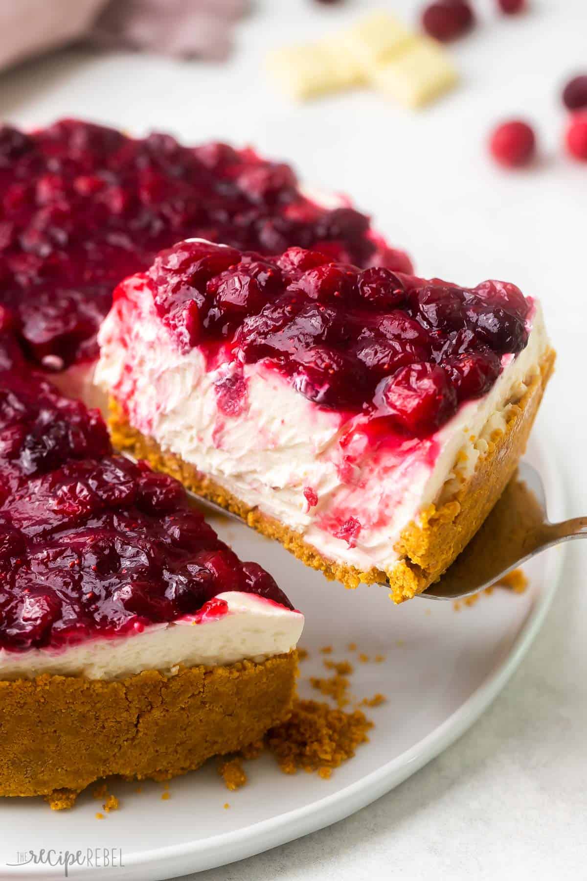 a piece of cheesecake being lifted off of a white plate.