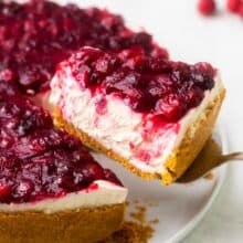 a piece of white chocolate cranberry cheesecake being lifted off of a plate.