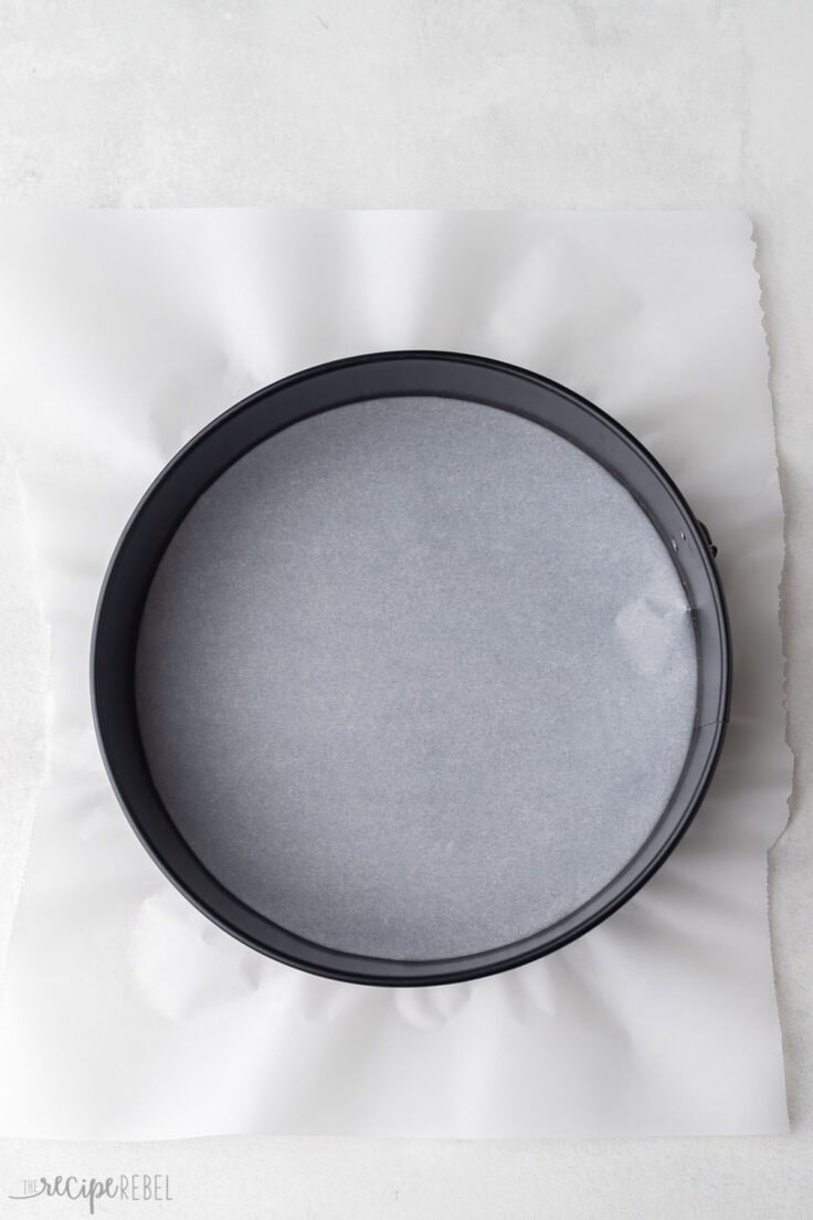 grey spring form pan with parchment paper in the bottom.