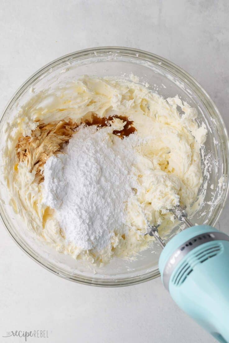 glass mixing bowl with cream cheese and other ingredients added on top.