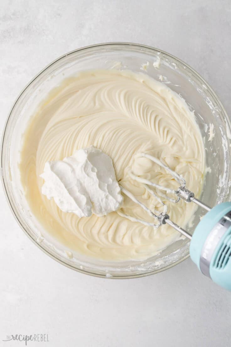 whipped cream added to glass mixing bowl with other mixed ingredients.